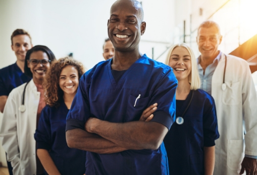 male hospital worker standing with his arms crossed in front of 5 other workers