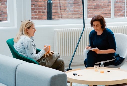 two women sitting around a table discussing.