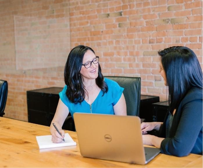 two women discussing around a laptop